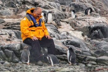 Wonder Voyage Executive Director Shawn Small visiting with penguins in Antarctica for blog post about transformative global travel