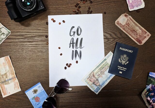 image of passport, camera, and sign that says "go all in" for Wonder Voyage blog post about mission trip prep