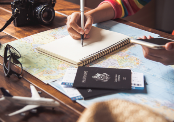 woman holding pen, notebook, phone, and passport for blog post about planning a transformational mission trip