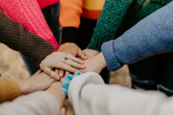 teens piling hands together for blog about mission trips for youth groups