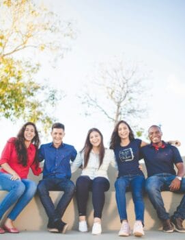 teens sitting on concrete bench smiling for blog about about mission trips for youth groups