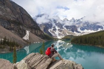traveler sitting on a mountain overlooking the blue water in Banff, Canada